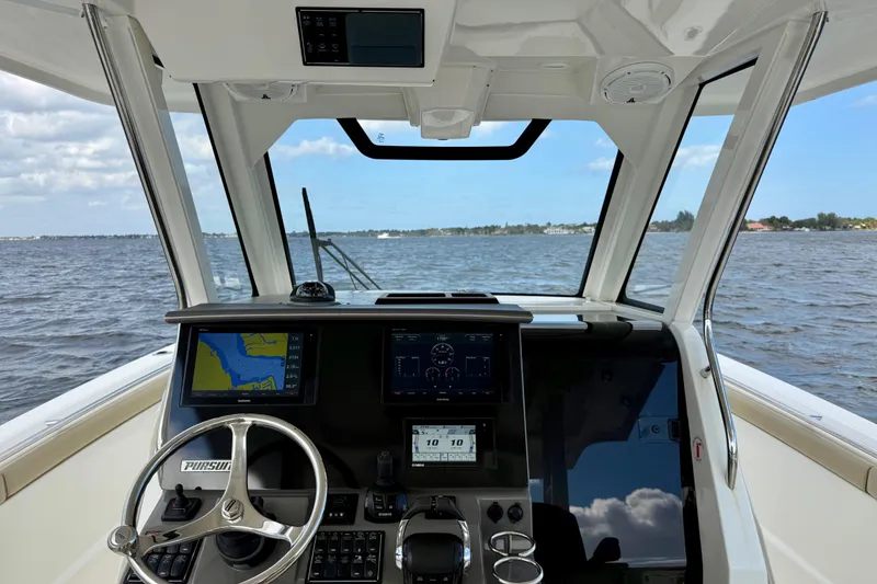 Slide: The Image of 2019 Pursuit S 328 Sport boat cockpit with navigation screens and steering wheel on open water. - 3