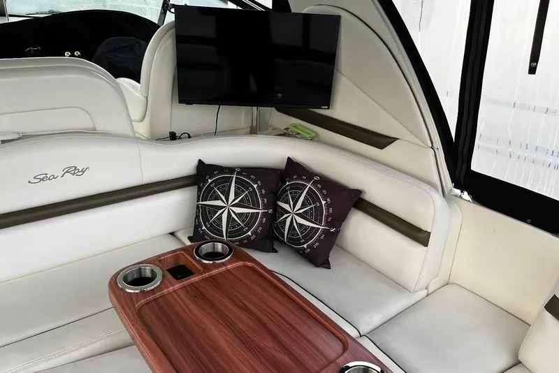 Slide: The Image of Interior of 2007 Sea Ray 38 Sundancer with white seating, TV, and compass-themed pillows. - 17
