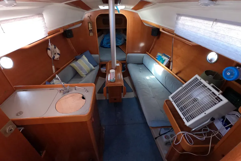 Slide: The Image of Interior of a 1990 Beneteau First 285 sailboat, featuring cozy seating and compact kitchen area. - 10