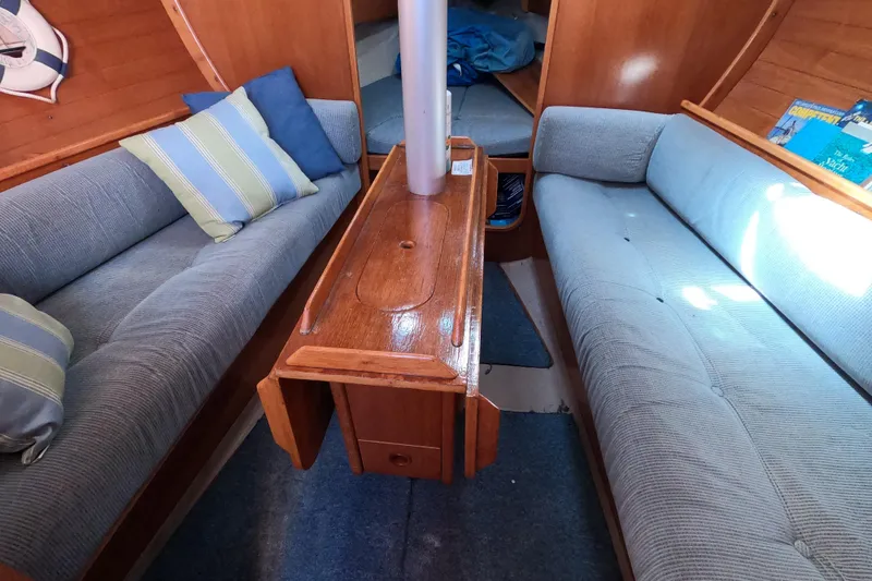 Slide: The Image of Interior of 1990 Beneteau First 285 sailboat with cozy seating and wooden table. - 11