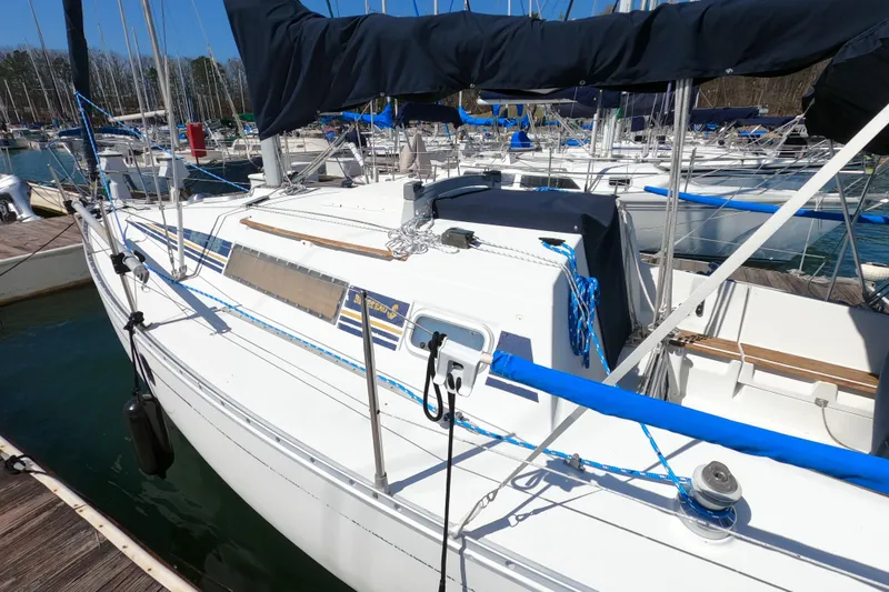 Slide: The Image of 1990 Beneteau First 285 sailboat docked at marina, featuring sleek white design. - 2