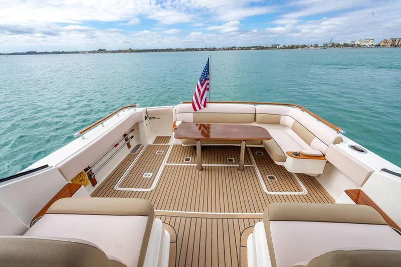 Slide: The Image of 2013 Tiara Yachts 3600 Coronet deck with seating, table, and American flag on calm water. - 9