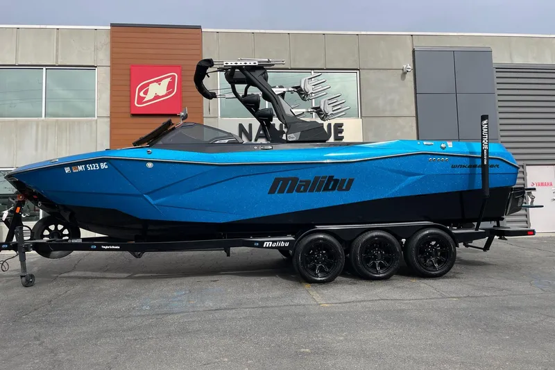 The Image of 2024 Malibu Wakesetter 26 LSV boat in vibrant blue on a trailer. - 1