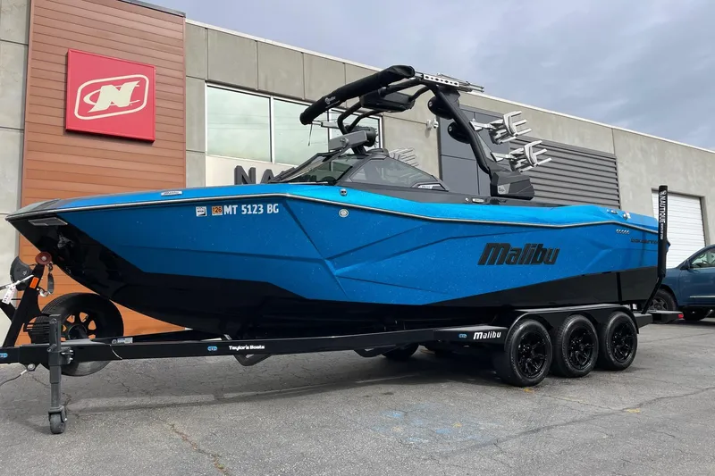Slide: The Image of 2024 Malibu Wakesetter 26 LSV boat in vibrant blue on a trailer. - 2