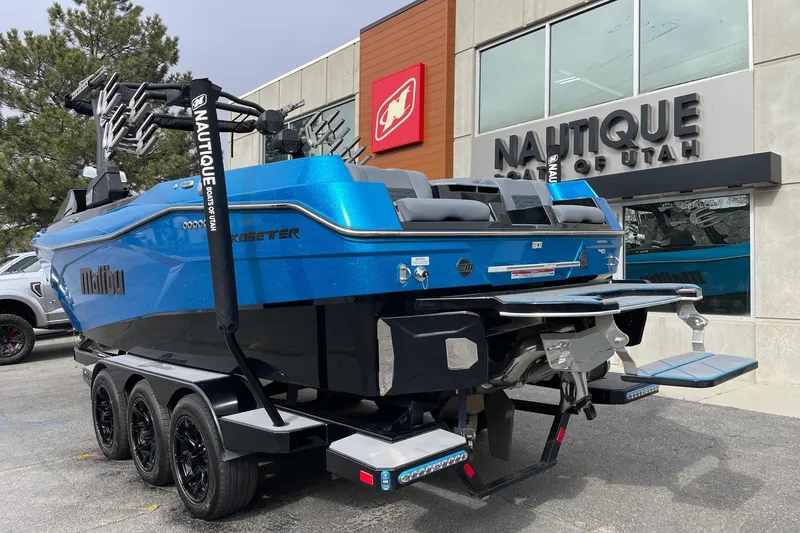Slide: The Image of 2024 Malibu Wakesetter 26 LSV boat in blue, parked outside Nautique dealership. - 3