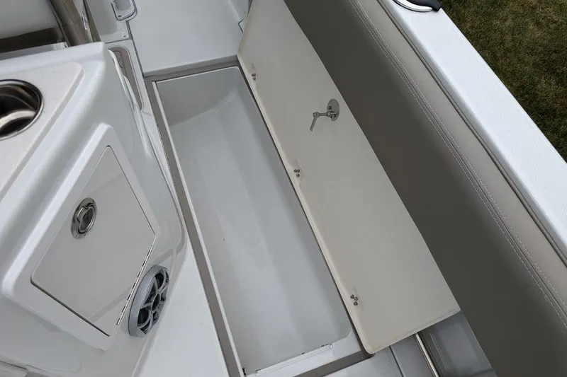 Slide: The Image of 2024 Finseeker 220 CC boat storage compartment with open lid and cup holder. - 16