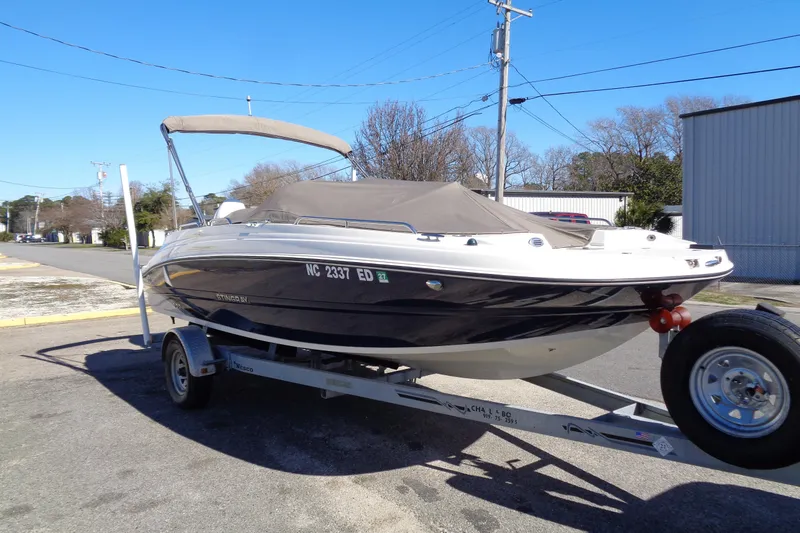 Slide: The Image of 2016 Stingray 192 SC boat on trailer, parked outdoors under clear blue sky. - 4