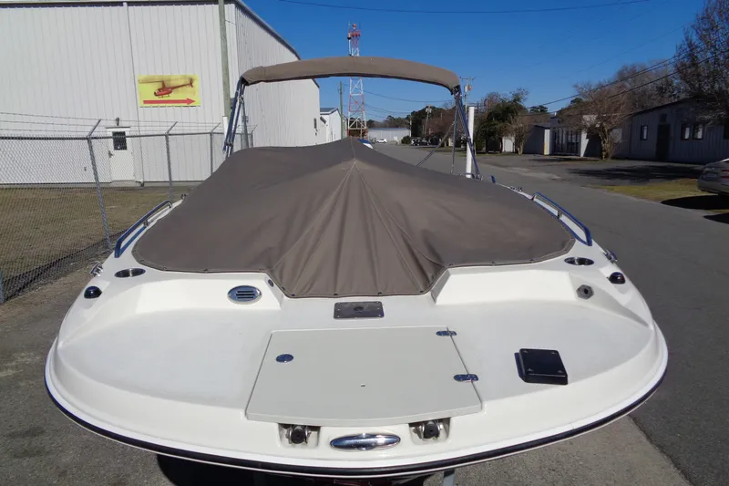 Slide: The Image of 2016 Stingray 192 SC boat with cover, parked outdoors near industrial buildings. - 5