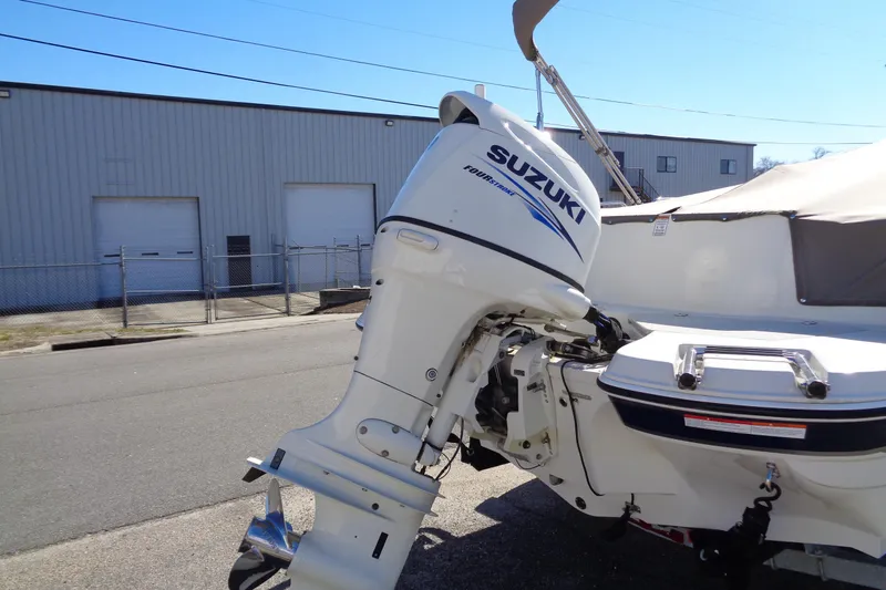 Slide: The Image of 2016 Stingray 192 SC boat with Suzuki outboard motor, parked near industrial building. - 7