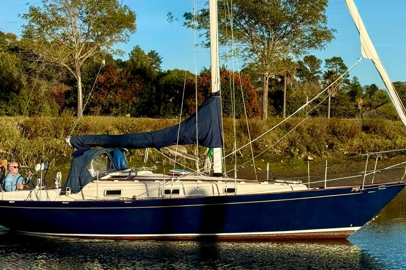 Slide: The Image of Sailboat Contessa 32, 1990 model, anchored near lush greenery and calm waters. - 2