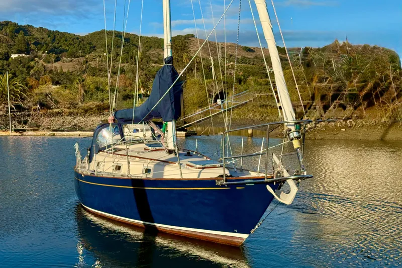 Slide: The Image of 1990 Contessa 32 sailboat on calm water with scenic hillside background. - 3
