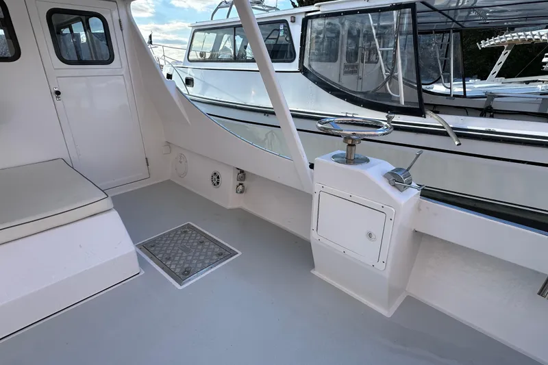 Slide: The Image of 2005 Evans 38 Chesapeake Bay Boat interior with seating and helm, docked beside another vessel. - 7