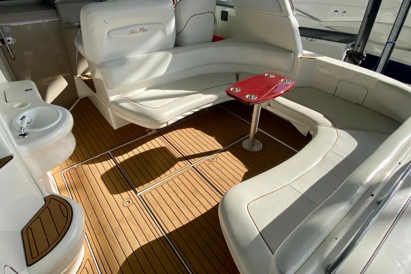 Slide: The Image of 1998 Sea Ray Sundancer 310 interior with white seating, wooden flooring, and a red table. - 25