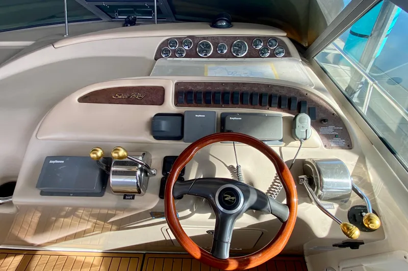Slide: The Image of 1998 Sea Ray Sundancer 310 helm with wooden steering wheel and navigation controls. - 29