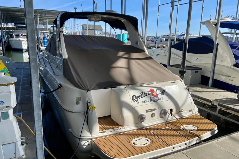 Slide: The Image of 1998 Sea Ray Sundancer 310 docked, covered, with wooden deck, in marina setting. - 3