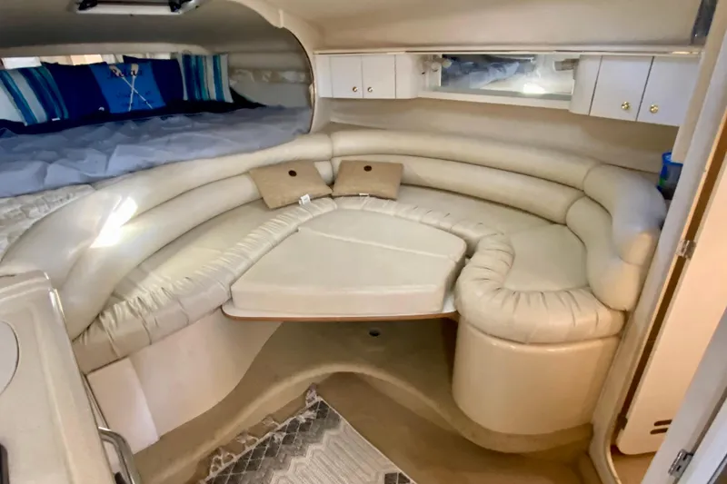 Slide: The Image of 1998 Sea Ray Sundancer 310 cabin interior with beige seating and cozy sleeping area. - 32