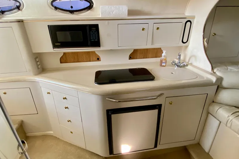 Slide: The Image of 1998 Sea Ray Sundancer 310 galley with microwave, sink, and storage cabinets. - 33