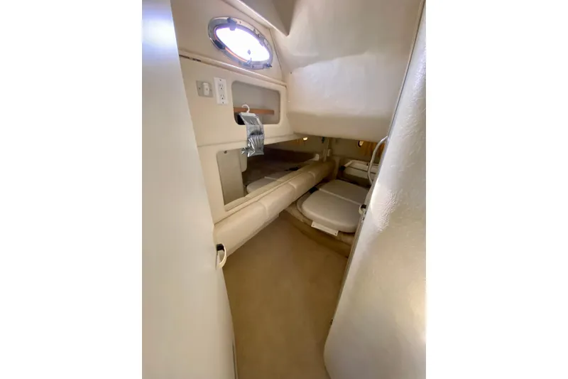 Slide: The Image of 1998 Sea Ray Sundancer 310 cabin interior with beige upholstery and porthole window. - 37