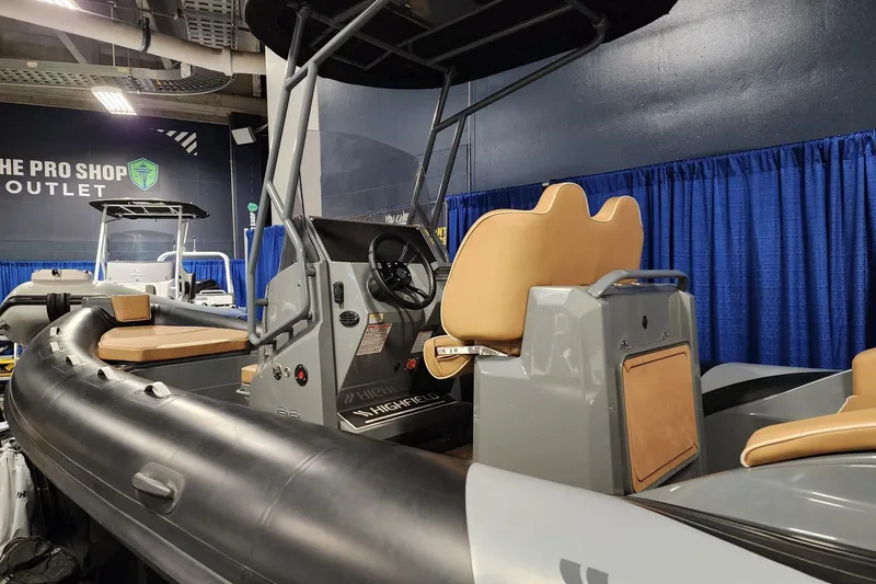 Slide: The Image of 2026 Highfield Escape 650 boat displayed at a showroom with blue curtains. - 6