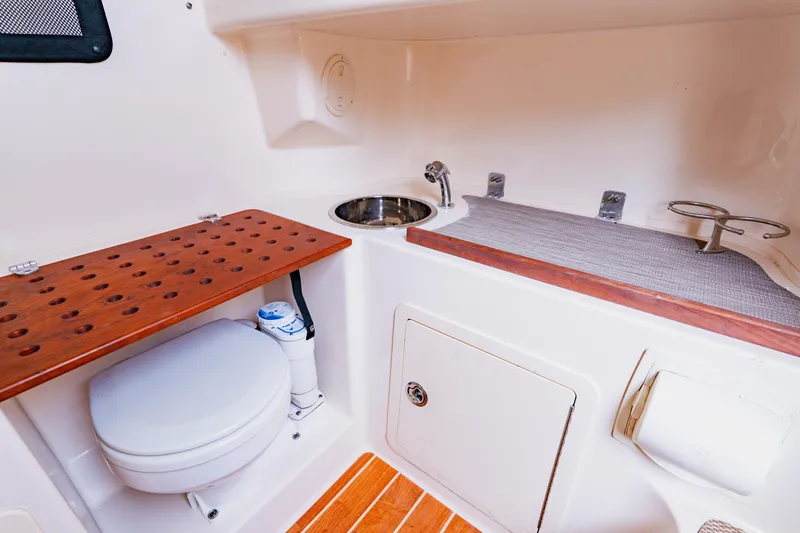 Slide: The Image of 2021 Grady-White Canyon 306 boat interior with toilet, sink, and wooden accents. - 46