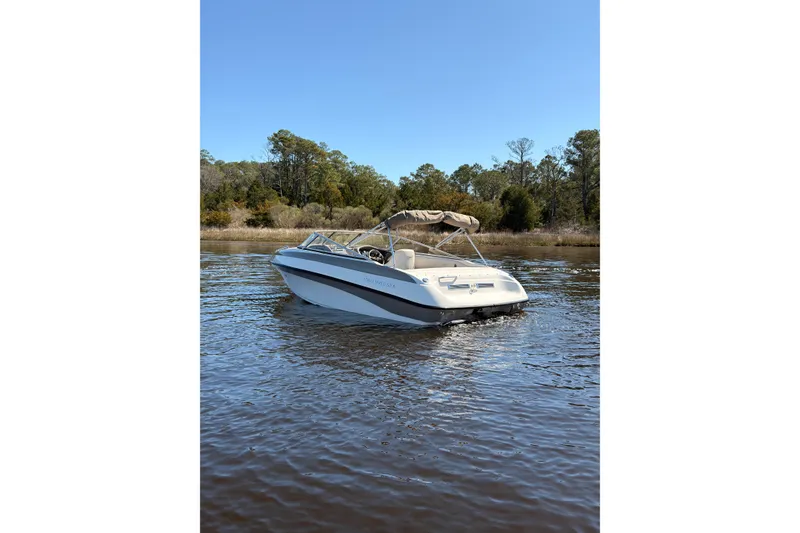 Slide: The Image of 2003 Crownline 180 BR boat on calm water with trees in the background. - 3