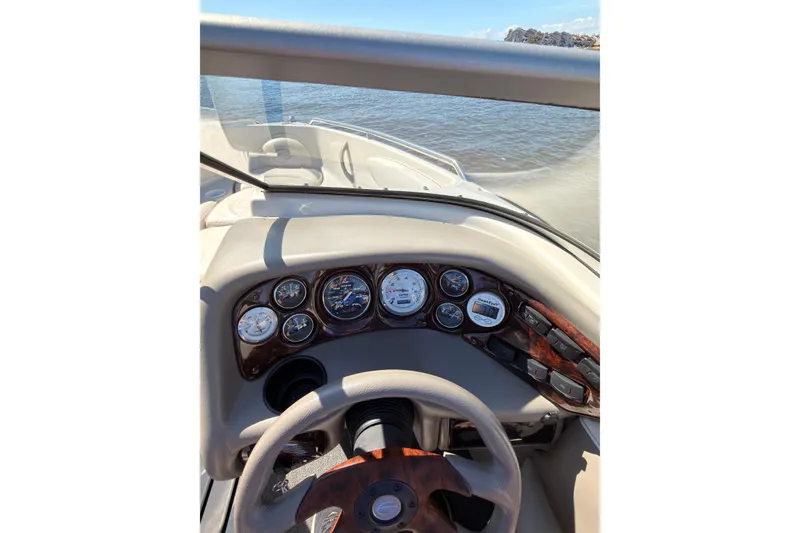 Slide: The Image of 2003 Crownline 180 BR boat dashboard with gauges and steering wheel, on calm water. - 7