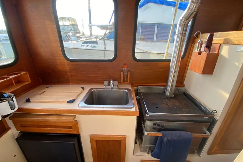 Slide: The Image of 1988 Nordic Tug 26 interior kitchen with sink, stove, and wooden cabinetry. - 11