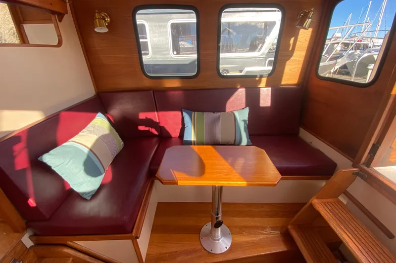 Slide: The Image of Cozy interior of 1988 Nordic Tug 26 with red seating, pillows, and wooden table. - 12