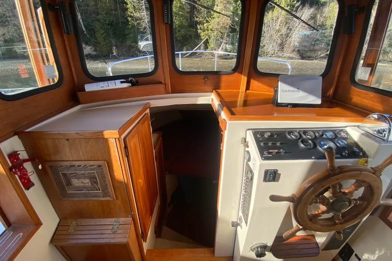 Slide: The Image of 1988 Nordic Tug 26 interior with wooden helm, Garmin navigation, and cabin entrance. - 13
