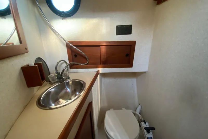 Slide: The Image of 1988 Nordic Tug 26 bathroom with sink, toilet, and wooden storage cabinet. - 21