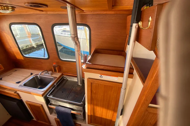 Slide: The Image of 1988 Nordic Tug 26 interior with wood finish, sink, and stove. - 23