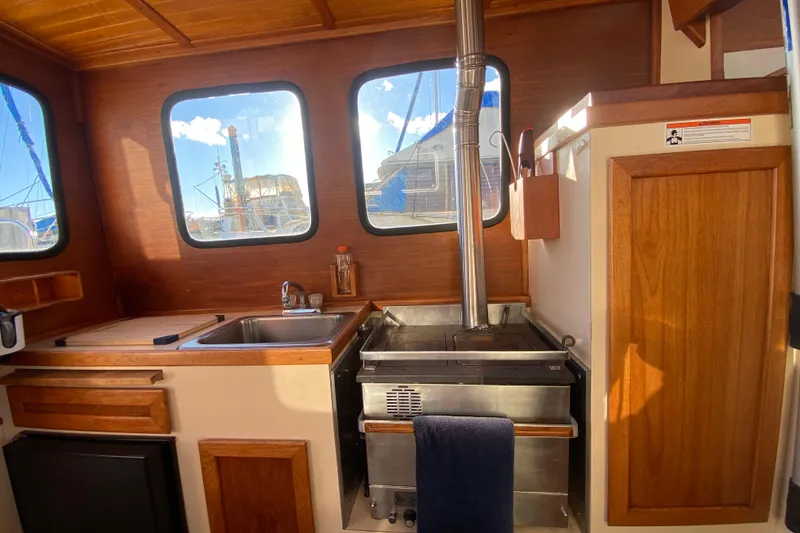 Slide: The Image of 1988 Nordic Tug 26 interior with wood finish, kitchen sink, and stove. - 25