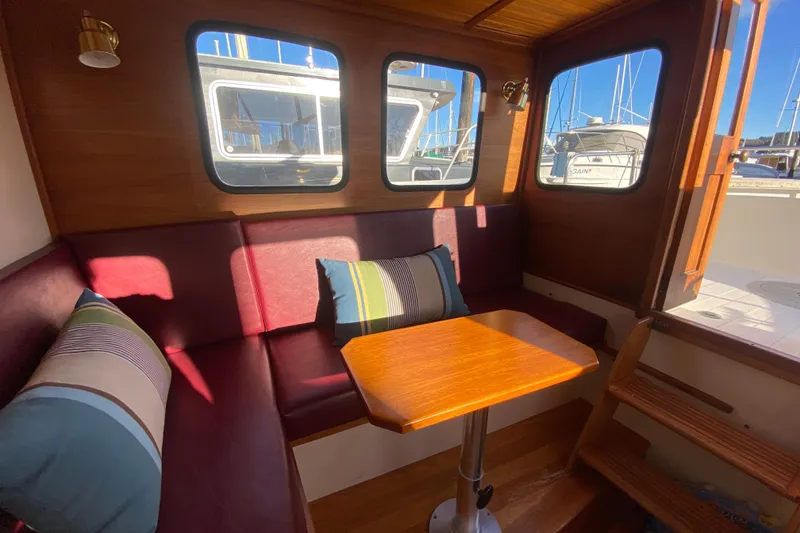 Slide: The Image of Cozy interior of 1988 Nordic Tug 26 with wooden table and cushioned seating. - 26