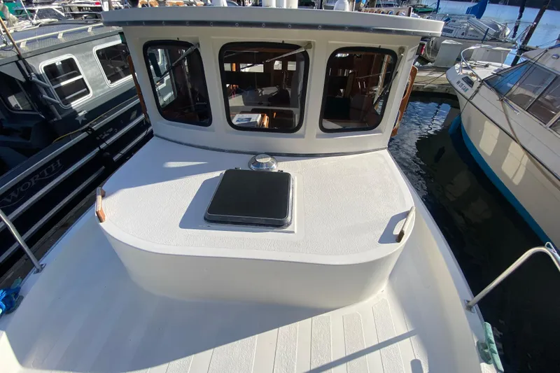 Slide: The Image of 1988 Nordic Tug 26 boat docked, showcasing cabin windows and deck details. - 5