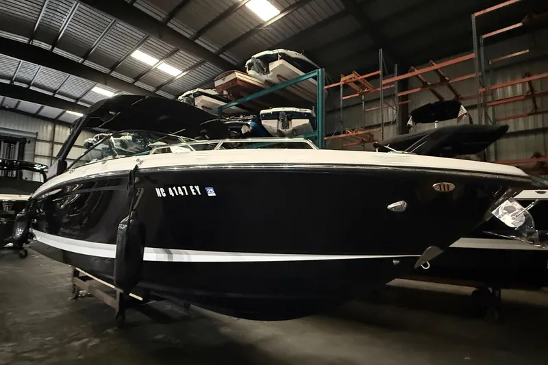 Slide: The Image of 2022 Chaparral 307 SSX boat in storage, sleek black design, indoor warehouse setting. - 20