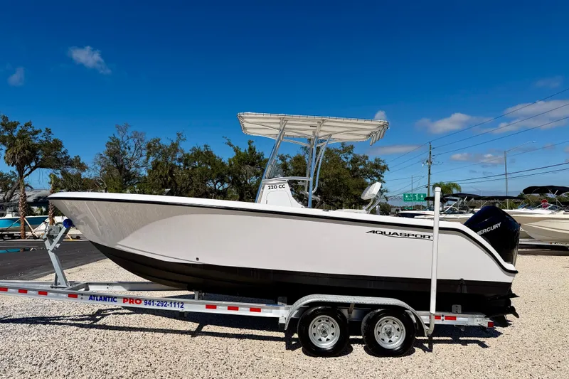 The Image of 2023 Aquasport 2200 Center Console boat on trailer under clear blue sky. - 0