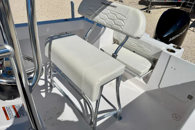Slide: The Image of 2023 Aquasport 2200 Center Console boat interior with white seating and Mercury engine. - 13