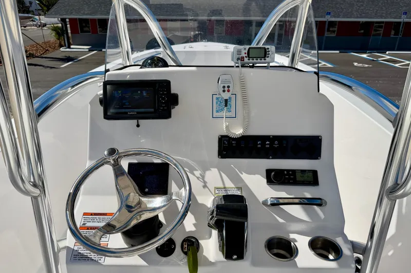 Slide: The Image of 2023 Aquasport 2200 Center Console boat dashboard with steering wheel and navigation equipment. - 16