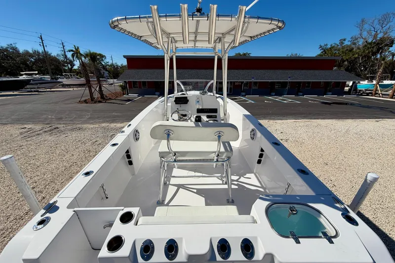 Slide: The Image of 2023 Aquasport 2200 Center Console boat with T-top and seating, parked outdoors. - 23