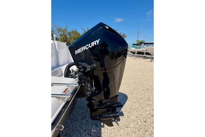 Slide: The Image of 2023 Aquasport 2200 Center Console with Mercury outboard engine, parked on gravel. - 29