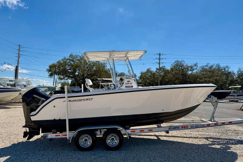 Slide: The Image of 2023 Aquasport 2200 Center Console boat on trailer under clear blue sky. - 4
