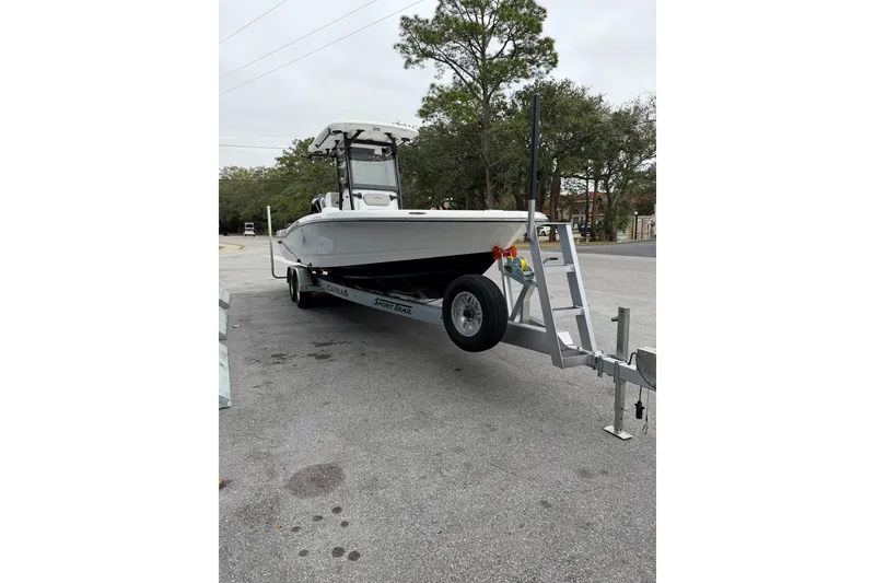 Slide: The Image of 2026 Caymas 28 HB boat on trailer in parking lot, surrounded by trees. - 2