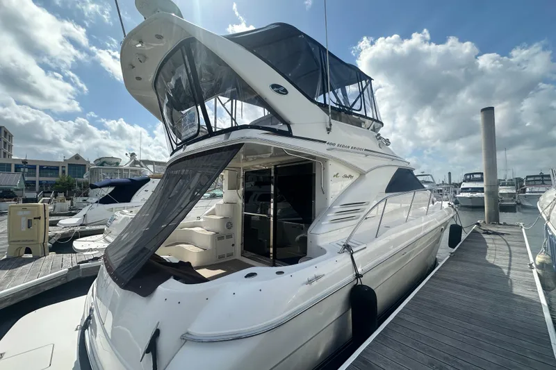 The Image of 1997 Sea Ray 400 Sedan Bridge yacht docked at marina under cloudy sky. - 0