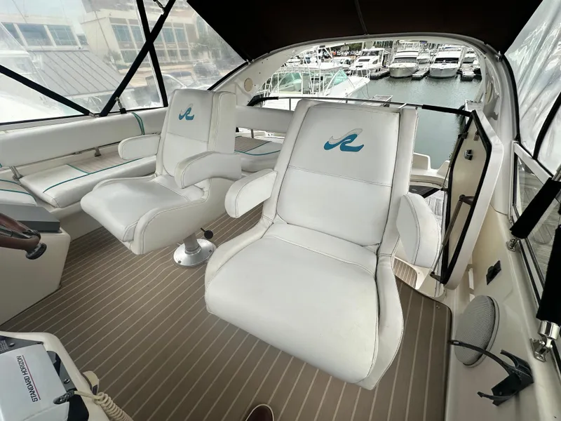 Slide: The Image of 1997 Sea Ray 400 Sedan Bridge interior with white seating and marina view. - 20