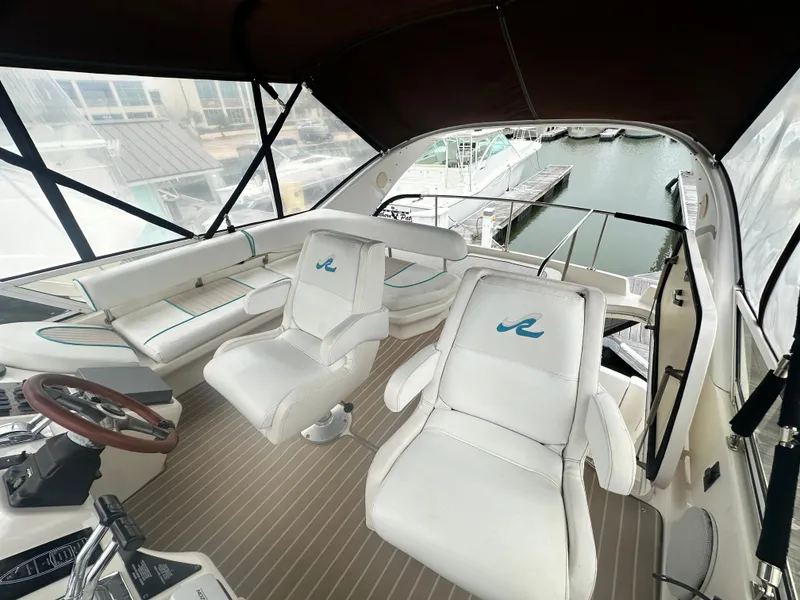 Slide: The Image of 1997 Sea Ray 400 Sedan Bridge yacht interior with white seating and marina view. - 21