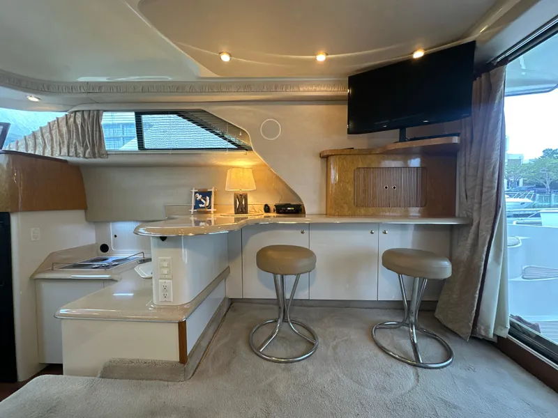 Slide: The Image of Interior of 1997 Sea Ray 400 Sedan Bridge with bar stools and TV. - 27