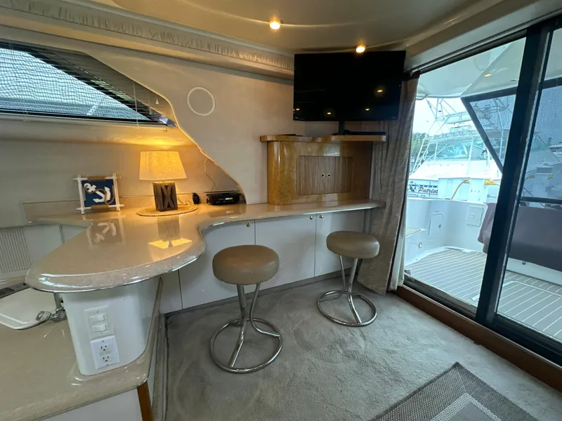 Slide: The Image of Interior of 1997 Sea Ray 400 Sedan Bridge with bar stools and TV. - 31
