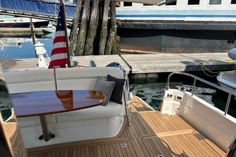 Slide: The Image of 2025 Sabre 48 Salon Express yacht deck with seating, table, and American flag. - 10