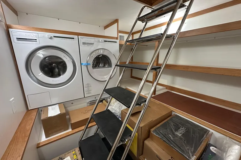 Slide: The Image of Laundry room with washer, dryer, ladder, and shelves on a 2025 Sabre 48 Salon Express. - 15