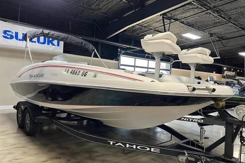 The Image of 2017 Tahoe 2150 boat on trailer in showroom, featuring dual seats and canopy. - 0